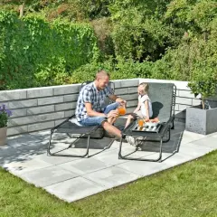 En far och dotter njuter av saft på en stenlagd uteplats. En vacker inspiration för en avkopplande trädgårdsmiljö.