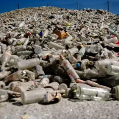 Enorm hög med glasflaskor och burkar, redo för glass recycling. En påminnelse om vikten av återvinning.