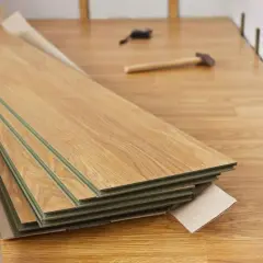 Nytt laminatgolv i kartong, redo att såga laminatgolv. Verktyg som hammare och kilar ligger utspridda.