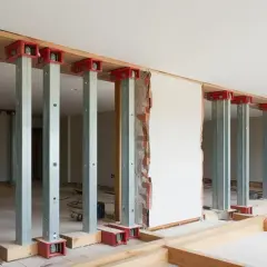 Stålbalk dimensionering pågår i ett rum under renovering. Flera pelare av stål stöttar upp en bjälke, redo för att bära tyngre laster.