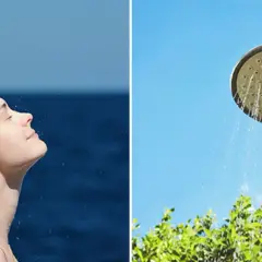 En kvinna njuter av en utedusch med insynsskydd av grönska. Vatten strömmar från en duschmunstycke mot en klarblå himmel.