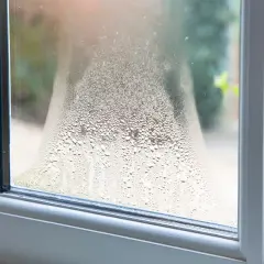 Kondens på fönstret, som om det blåser i ventilationen. Vattendroppar bildar ett mönster på glaset.