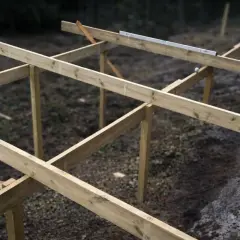 Träkonstruktion för altan byggs. Grus under altan syns tydligt.