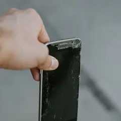En hand håller en trasig Samsung-mobil. Dags att återvinna mobiltelefonen för att spara på jordens resurser.