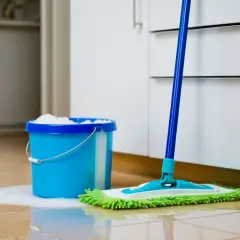 Blå hink med såpa och en mopp redo att såpa golv grumme.