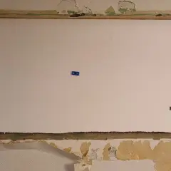 En stor vit cellplastskiva är monterad i en nisch. Blå fästen håller skivan på plats.
