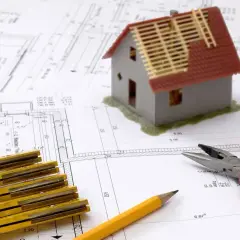 Ritningar för ett passivhus, en modell av ett hus, tumstock och tång. Planering för energieffektiva hem.