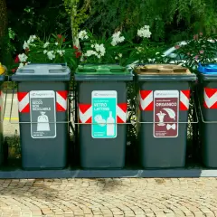 Fem sopsorteringskärl för återvinning, inklusive plast och papper. Inga kärl för farligt avfall syns.