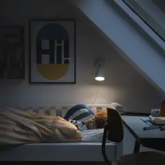 Barn sover i säng med randigt täcke. En lampa lyser över skrivbordet. God ventilation sovrum krav är viktigt för en god natts sömn.