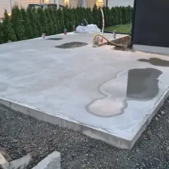 Nyligen gjuten betongplatta med vattenpölar, en påminnelse om att gjuta i regn kan vara utmanande.