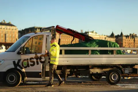 Man i varselkläder går bredvid en lastbil med kran, redo att återvinna aluminium.
