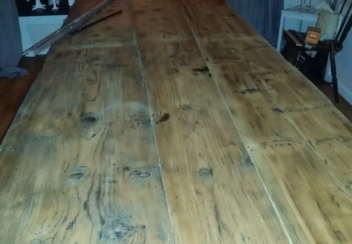 Ett långt, grovt såpskura bord av träplankor. Det ser ut att vara nyligen rengjort och redo för användning.