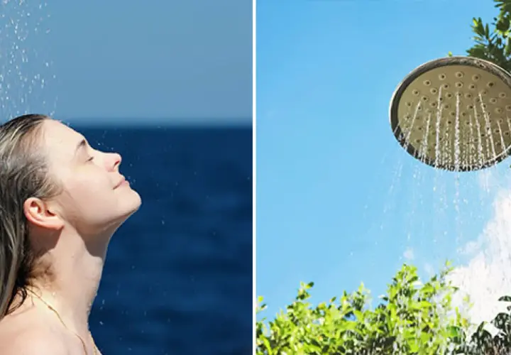 En kvinna njuter av en utedusch med insynsskydd av grönska. Vatten strömmar från en duschmunstycke mot en klarblå himmel.
