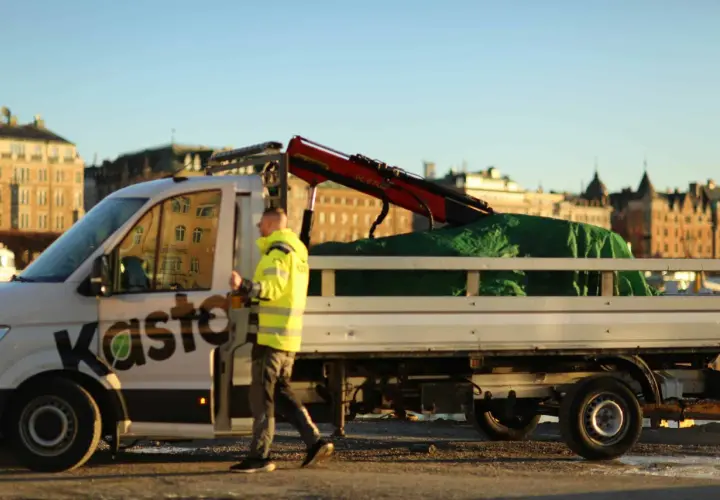 Man i varselkläder går bredvid en lastbil med kran, redo att återvinna aluminium.