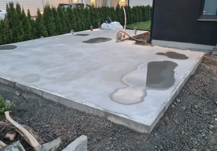 Nyligen gjuten betongplatta med vattenpölar, en påminnelse om att gjuta i regn kan vara utmanande.