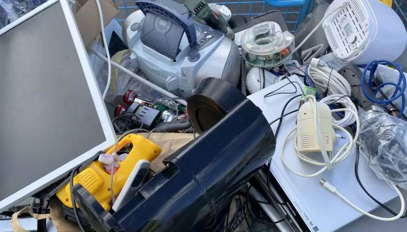 En vagn fylld med elektronik för återvinning av elektronik. En skärm, en stereo, sladdar och andra prylar.