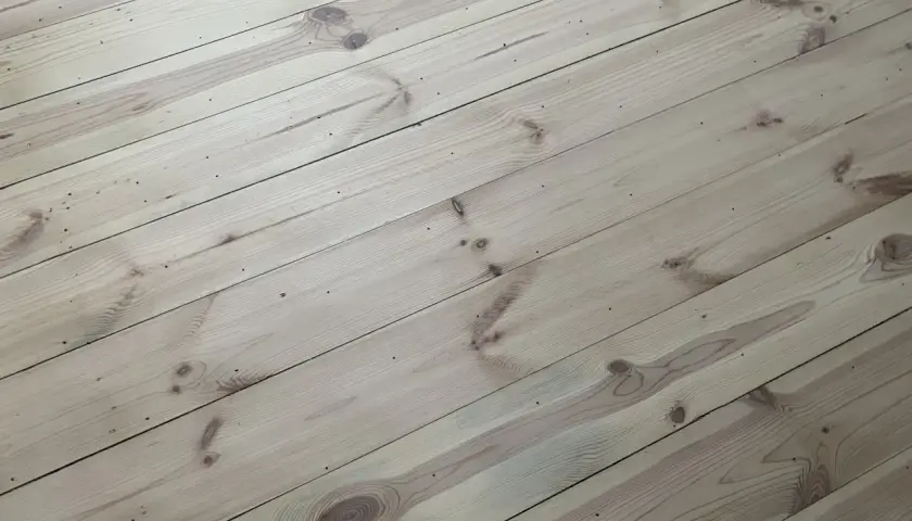 Ljust, obehandlat furugolv med synliga kvistar och ådringar. Golvet har en naturlig, rustik känsla.