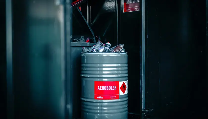 En grå tunna fylld med tomma sprayflaskor, märkt "AEROSOLER", redo för tomma sprayflaskor återvinning.