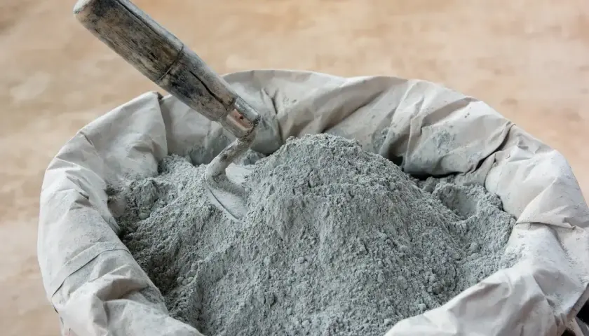 En säck med cement och betong, en murslev vilar i den gråa pulvret, redo för byggprojekt.