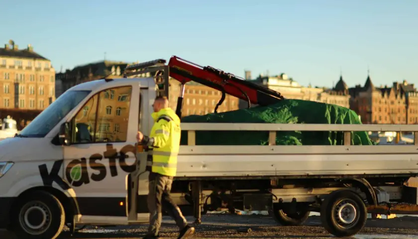 Man i varselkläder går bredvid en lastbil med kran, redo att återvinna aluminium.