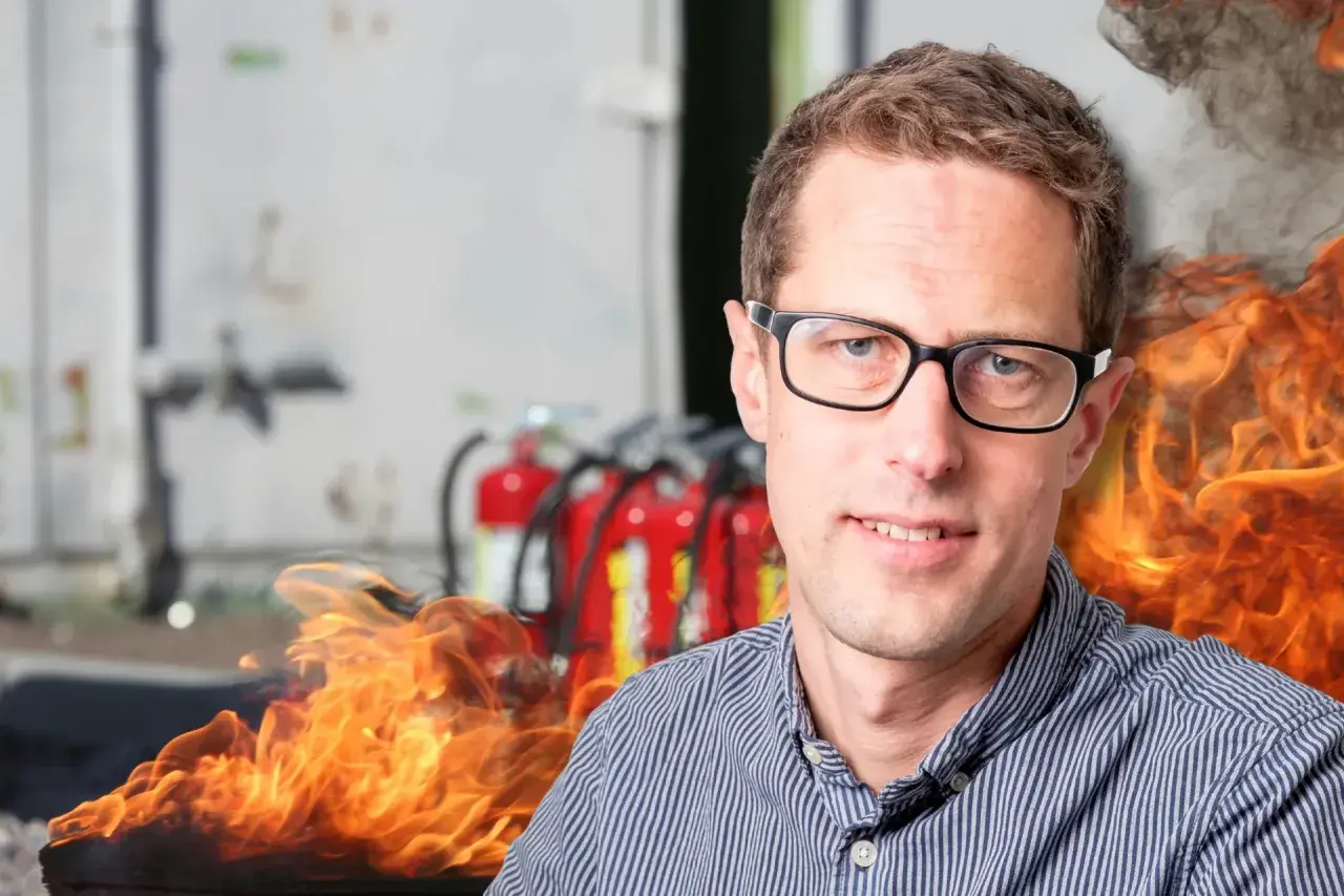 Man med glasögon framför brandsläckare och flammor. En påminnelse om vikten av boverkets byggregler och brandskydd.