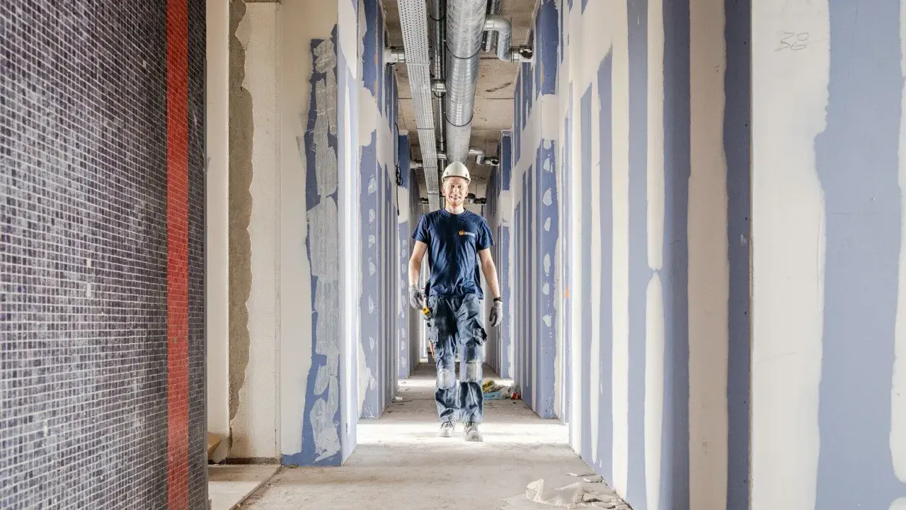 Byggarbetare i en korridor under provtryckning med luft. Rörsystem syns i taket.