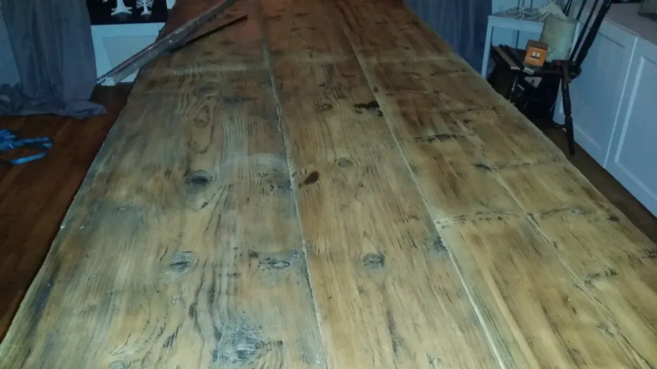 Ett långt, grovt såpskura bord av träplankor. Det ser ut att vara nyligen rengjort och redo för användning.