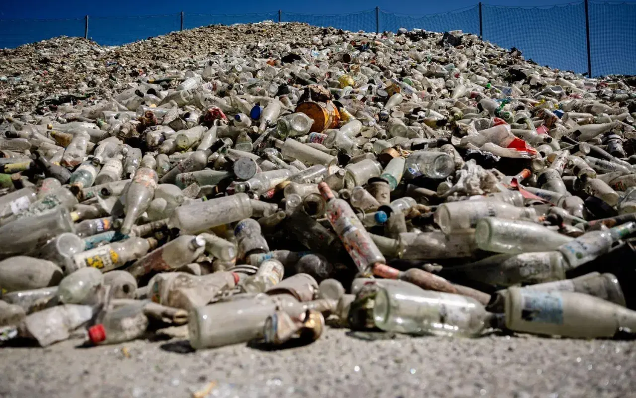 Enorm hög med glasflaskor och burkar, redo för glass recycling. En påminnelse om vikten av återvinning.