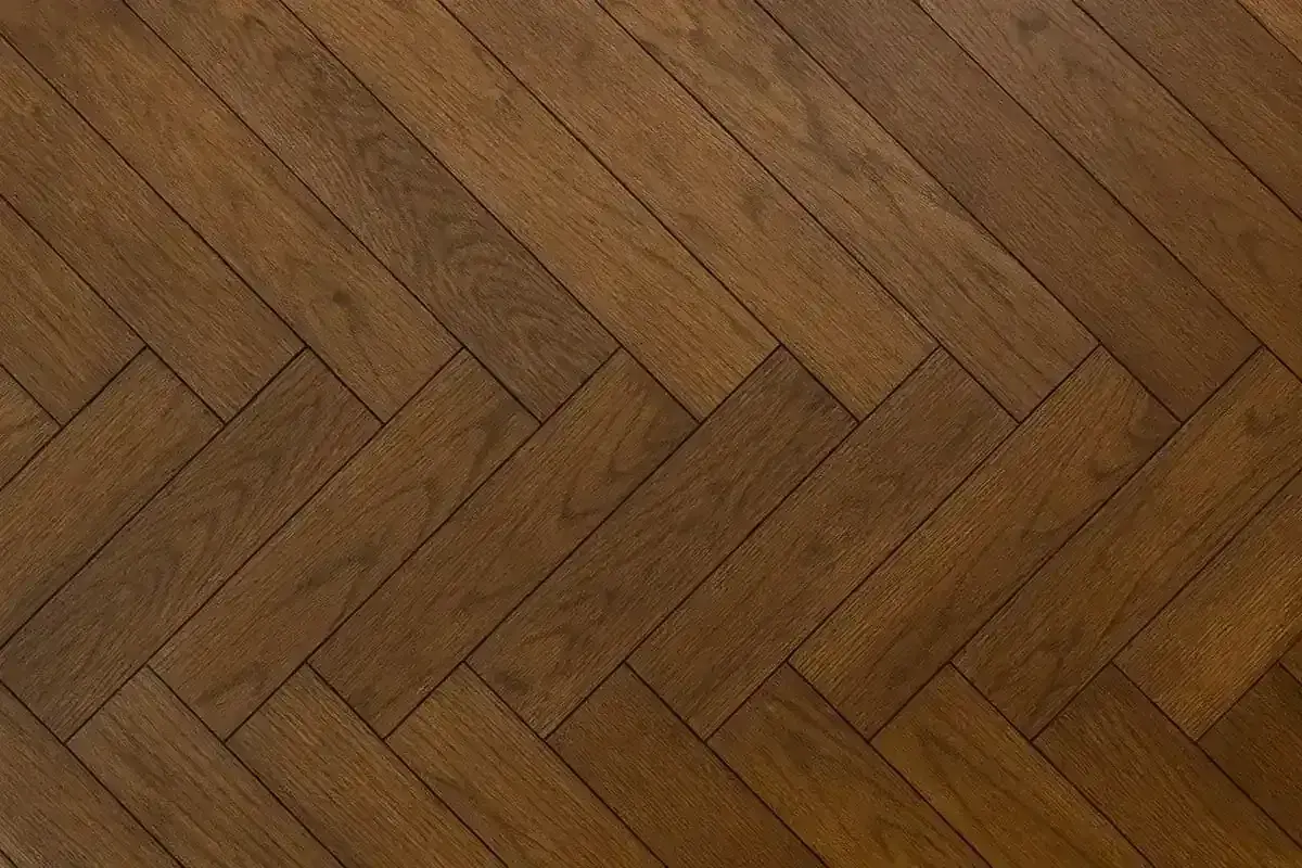 Ett vackert, mörkt gammalt plankgolv lagt i fiskbensmönster.