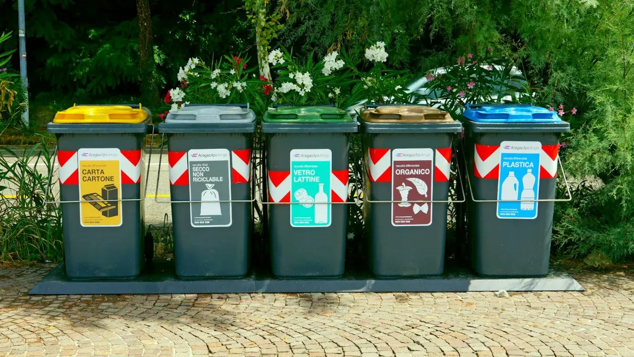Fem sopsorteringskärl för återvinning, inklusive plast och papper. Inga kärl för farligt avfall syns.