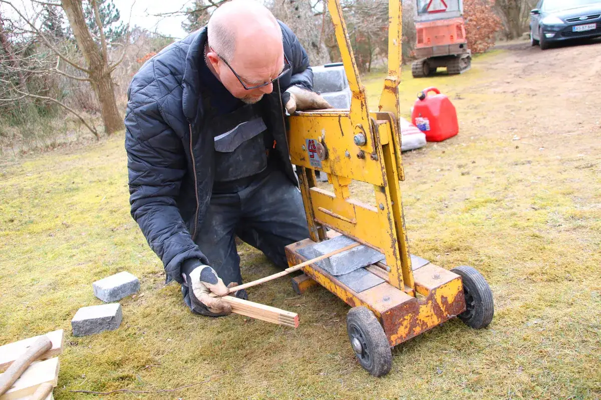 Man använder en maskin för att såga sten utomhus.