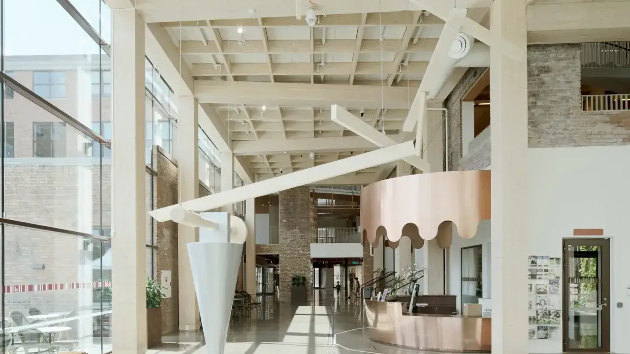 Ljus och luftig entréhall med synliga träbjälkar och koppardetaljer. En modern reception möter besökaren, där bbr ljudkrav har beaktats för en behaglig miljö.
