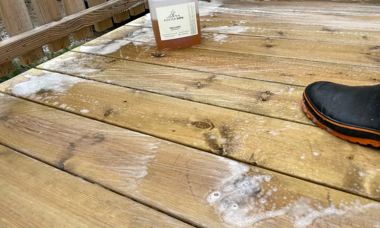 En flaska s&aring;pa st&aring;r p&aring; en altan som h&aring;ller p&aring; att behandlas med s&aring;pa. En st&ouml;vel syns i nedre h&ouml;gra h&ouml;rnet.