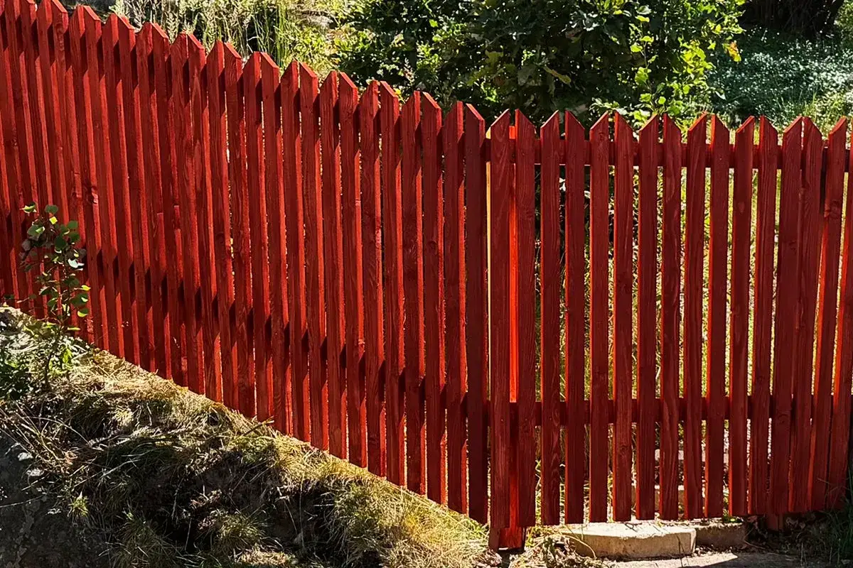 Nyligen f&auml;rdigst&auml;llt staket i en varm r&ouml;d nyans, redo att bygga in tr&auml;dg&aring;rden.