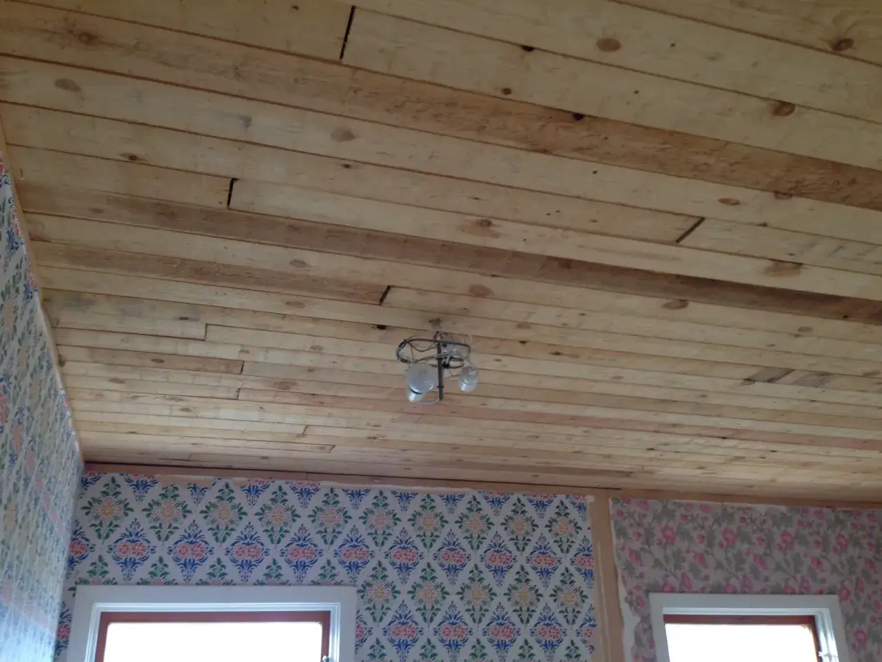 Taket är klätt med obehandlad furu inomhus. En taklampa hänger från träpanelen.