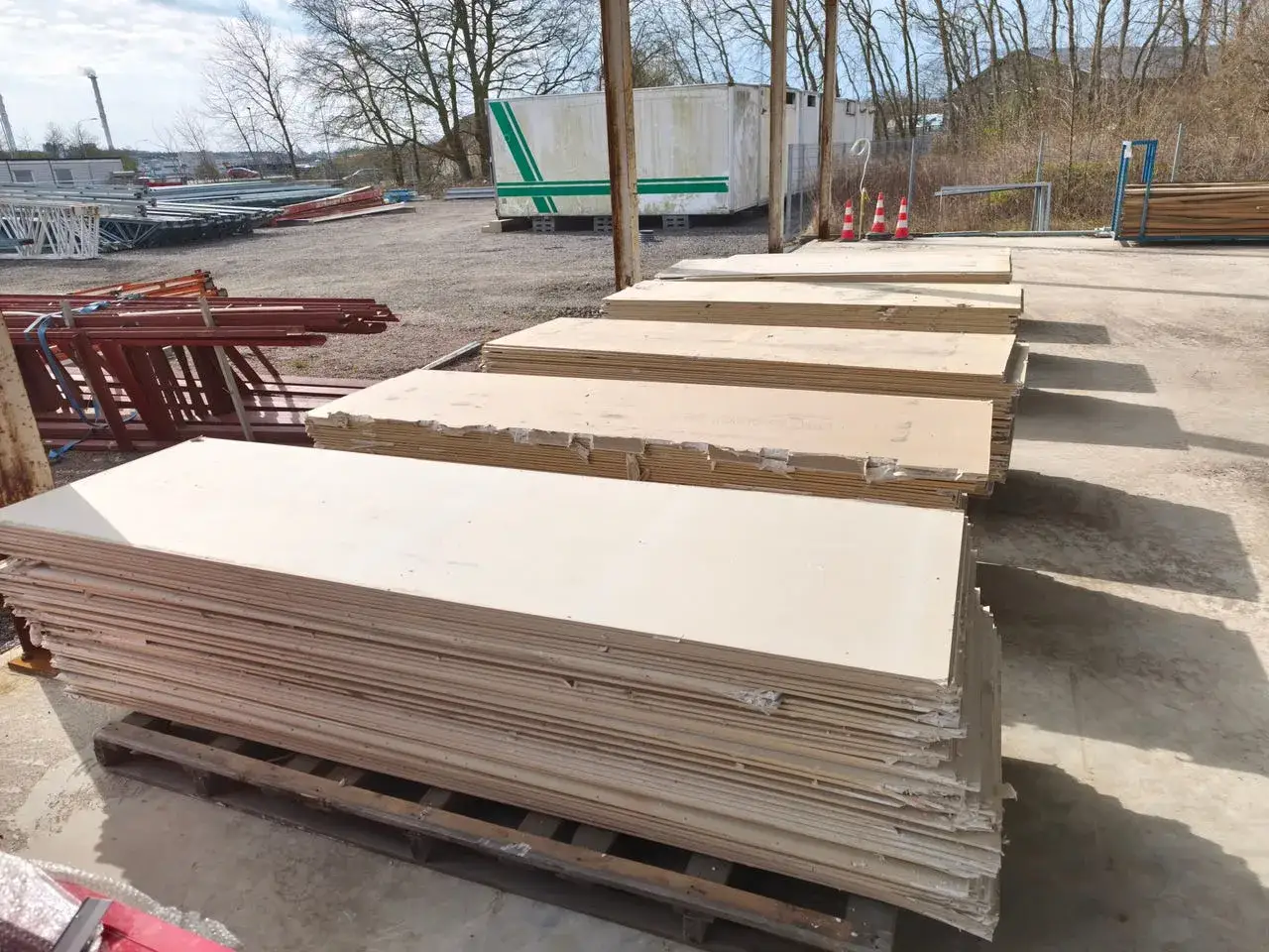 Staplade gipsskivor redo f&ouml;r gips &aring;tervinning. I bakgrunden syns byggmaterial och containrar.