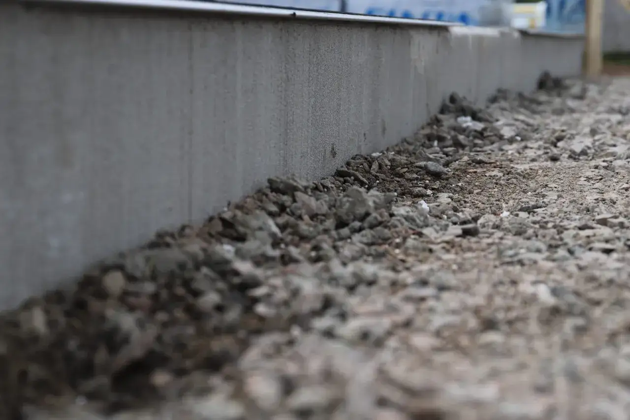 Gr&aring; betongkant med makadam i f&ouml;rgrunden. T&auml;nker p&aring; hur mycket makadam under platta som beh&ouml;vs f&ouml;r stabilitet.