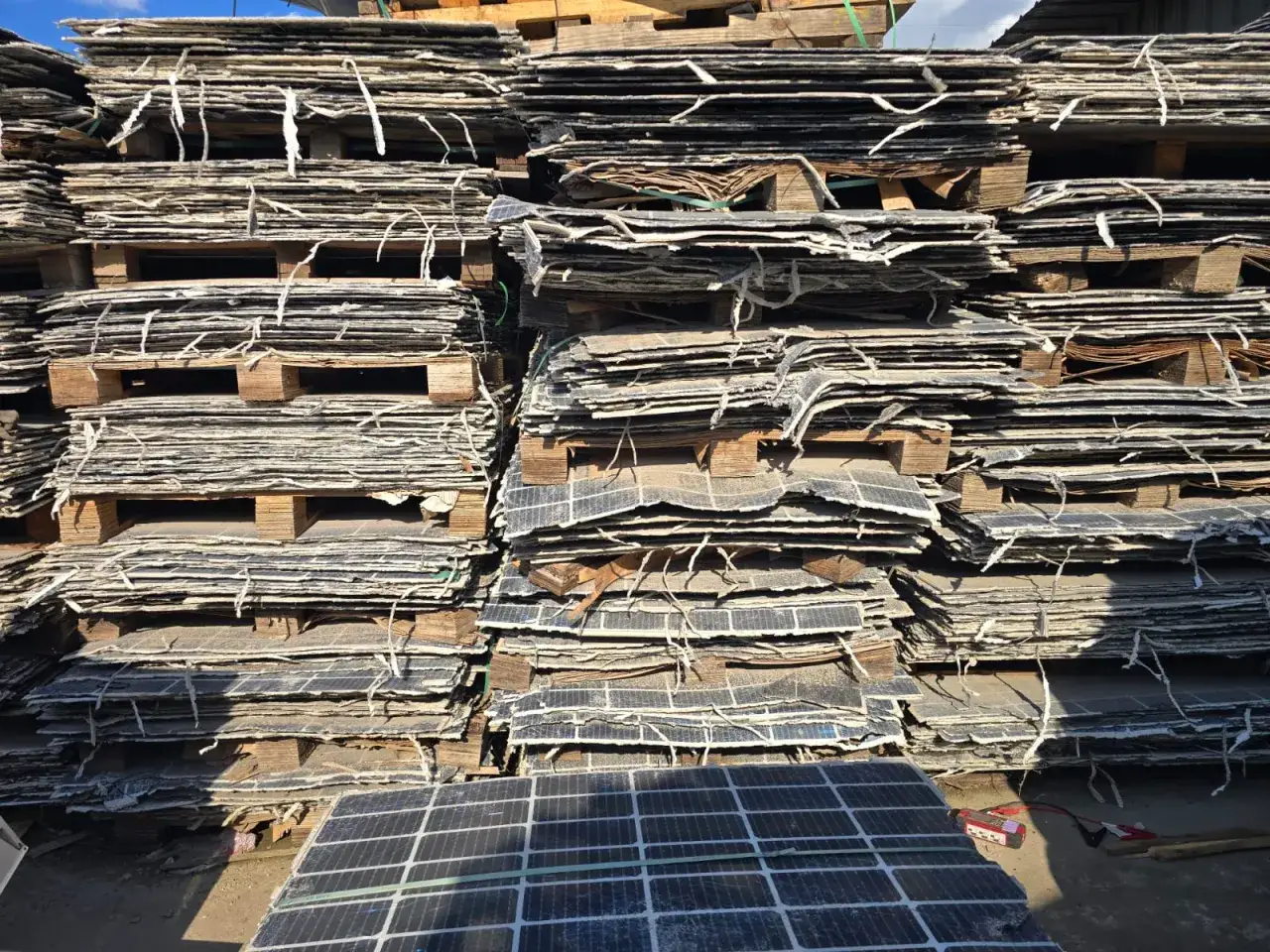 Staplade, slitna solcellspaneler på pallar, redo för återvinning av solceller. En ny början för materialen.